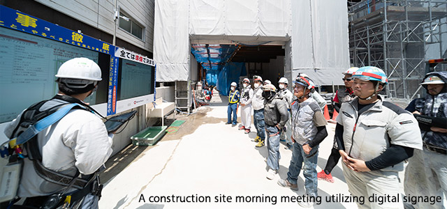 A construction site morning meeting utilizing digital signage